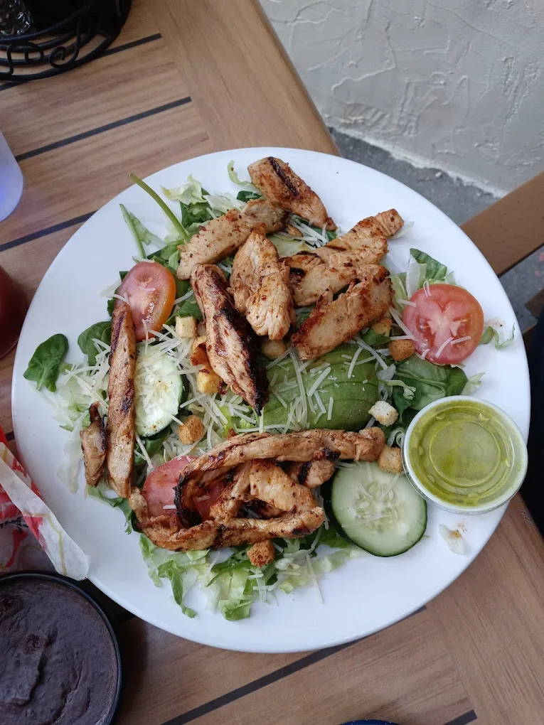 Avocado Chicken Salad - A fresh and vibrant salad with grilled chicken, creamy avocado, crisp lettuce, tomato, and cheese, served with our house dressing.