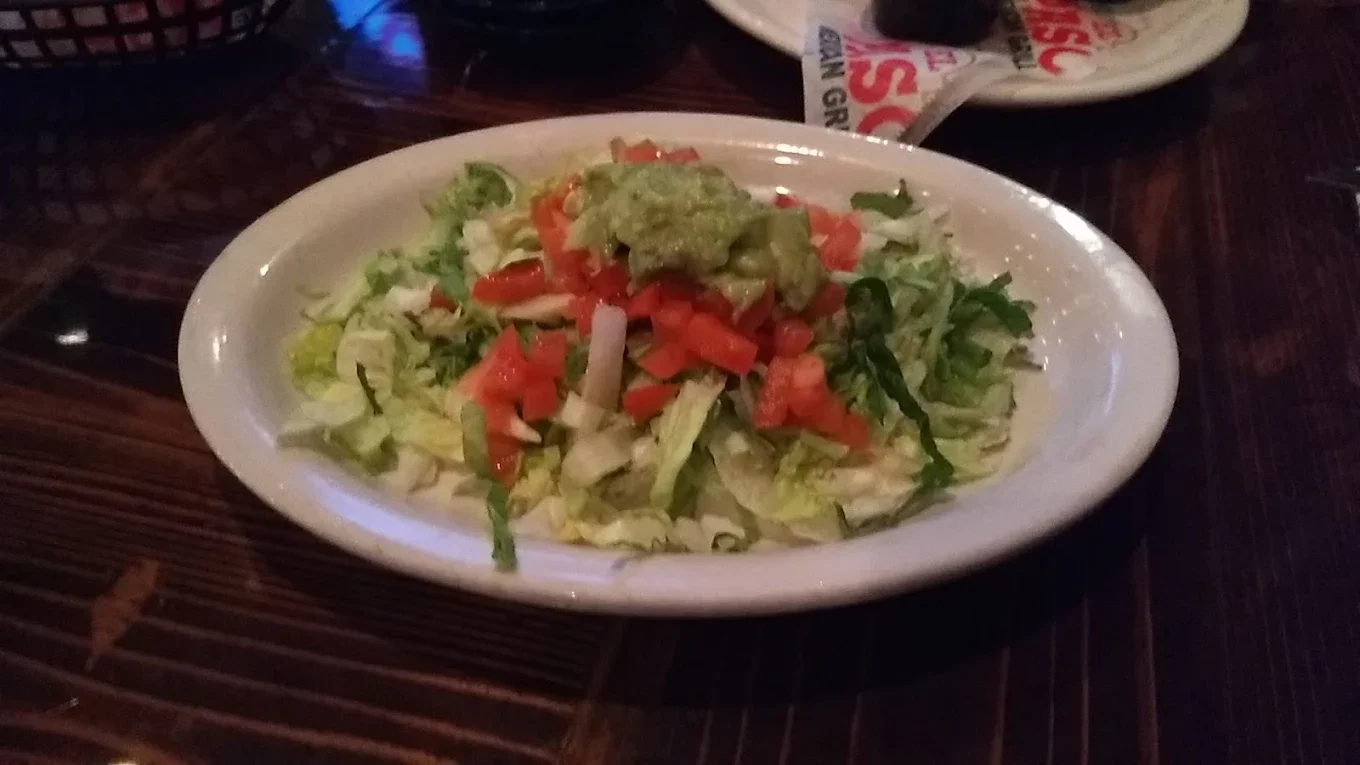 Guacamole Salad - Fresh guacamole served over crisp greens with tomato and cilantro
